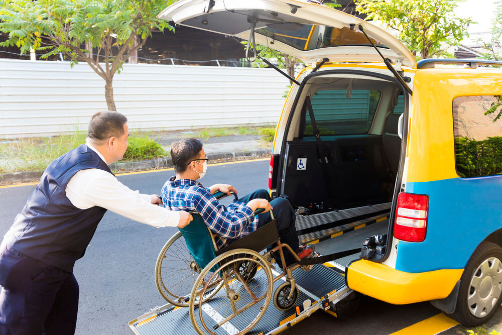 Uomo su sedia a rotelle caricato su un taxi per disabili